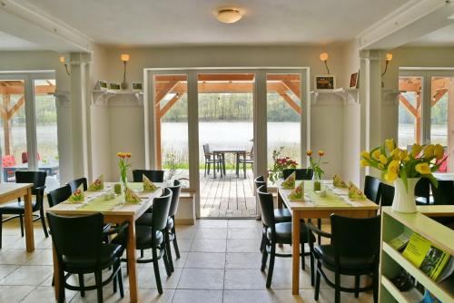 ein Restaurant mit Tischen und Stühlen und eine Terrasse in der Unterkunft Seehaus Hartwigsdorf in Klein Vielen