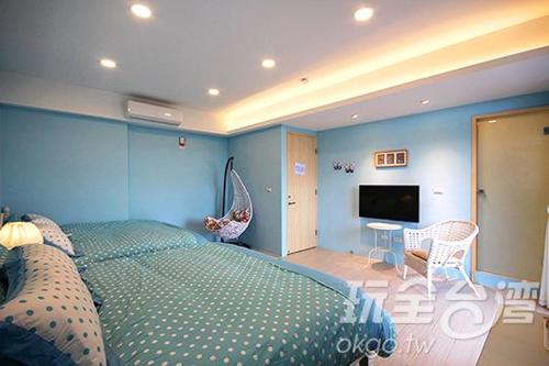 a blue bedroom with a bed and a flat screen tv at Sea People B&B in Magong
