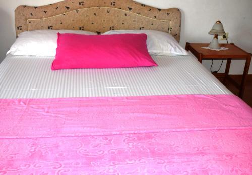 a pink pillow on a pink and white bed at Bisha Apartments in Ulcinj