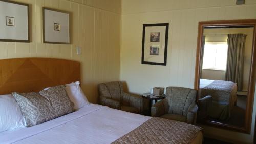 a hotel room with a bed and two chairs at The Amethyst Beach Motel in Point Pleasant Beach