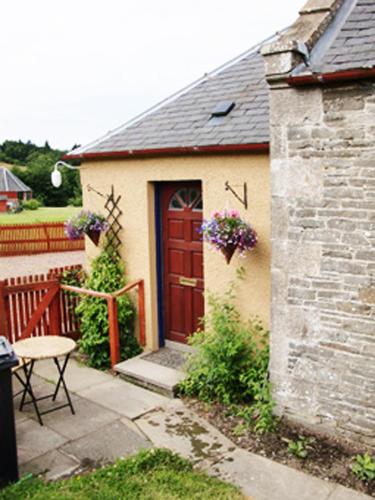 a small house with a red door and a patio at Martinshouse Holiday Cottage, Hawick, Borders in Hawick