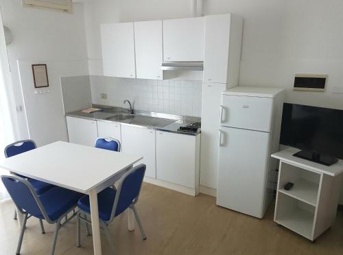 a kitchen with a white table and a white refrigerator at Hotel Residence Adriana in Cesenatico
