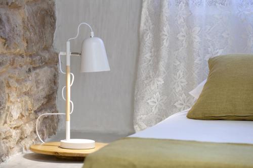 a white lamp on a table next to a bed at Voulamandis House in Kambos