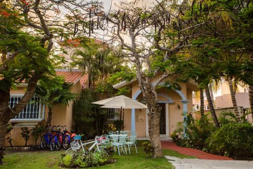 a patio with a table and chairs and an umbrella at Chez Waffle Hotel in Puerto Aventuras