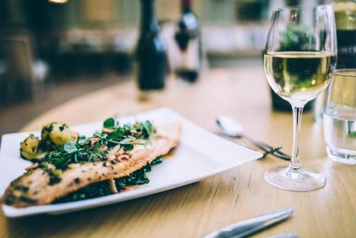 a plate of food and a glass of wine on a table at The Hoste and The Vine House Hotels in Burnham Market