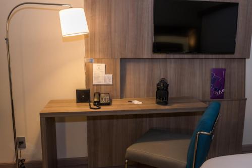a room with a desk with a phone and a lamp at Novotel RJ Praia de Botafogo in Rio de Janeiro