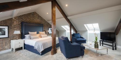 a bedroom with a large bed and two blue chairs at Giles Norman Gallery & Townhouse in Kinsale