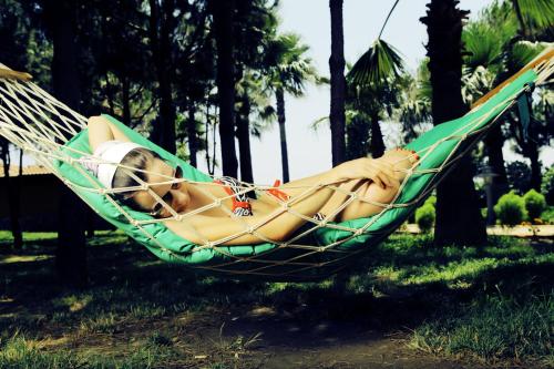 a woman laying in a hammock in a park at Club Turtas Beach - All Inclusive in Konaklı
