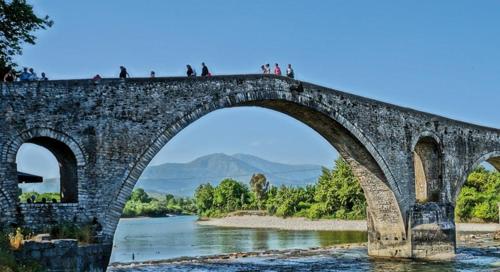 a stone bridge over a river with people walking on it at Koronisia Apartments in Koronisia