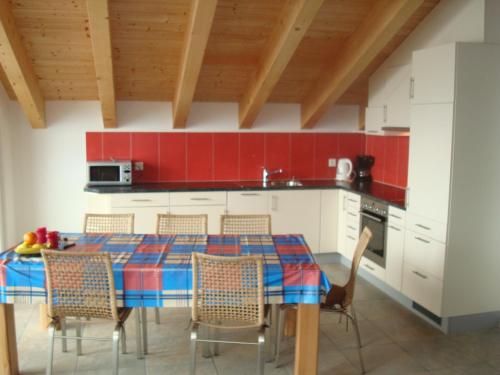 una cucina con un tavolo con sedie e pareti rosse di Apartment Amore a Riederalp