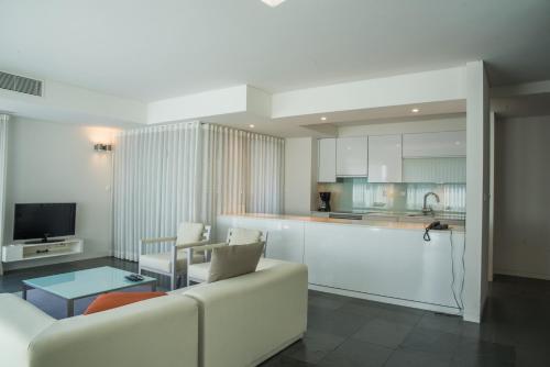 a living room with a white couch and a kitchen at Troia Residences - Apartamentos Ácala in Troia