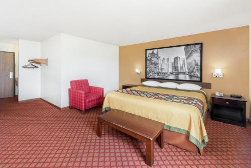 a hotel room with a bed and a red chair at Super 8 by Wyndham Marshall in Marshall