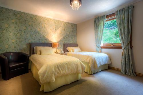 a bedroom with two beds and a chair and a window at Cairnryan Bed and Breakfast in Cairnryan