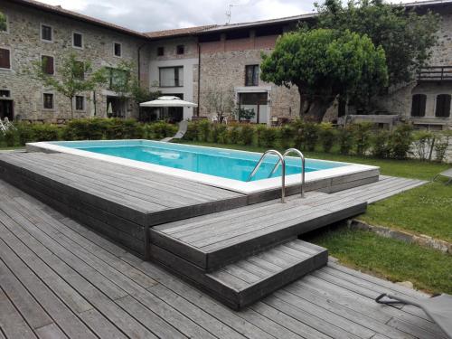 uma piscina com um deque de madeira e um edifício em Agriturismo Borgo Floreani em Vendoglio