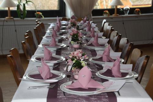 ミュンヒベルクにあるPension Fuchsbauの長テーブル(ピンクのナプキンと皿付)