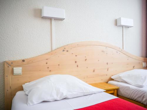 - une chambre avec une tête de lit en bois et 2 lits dans l'établissement Village Vacances Passion L'Estibère, à Vielle-Aure