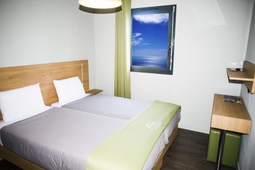 um quarto com uma cama grande e uma janela em All Suites Besançon em Besançon
