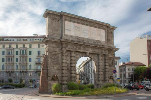 a large stone arch in a city with buildings at Hotel Piacenza in Milan