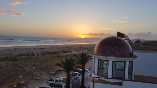 a sunset over the beach and a building with a dome at Gran Sol in Zahara de los Atunes