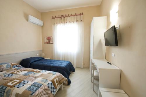 een kamer met 2 bedden, een tv en een raam bij Vela Latina Affittacamere in Marsala