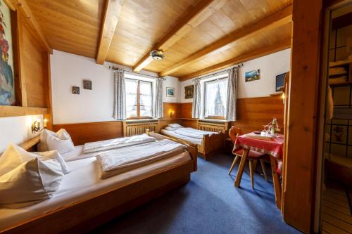 two beds in a room with a red table at Hotel & Gasthof Fraundorfer in Garmisch-Partenkirchen