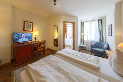 a hotel room with a bed and a flat screen tv at Hotel & Gasthof Fraundorfer in Garmisch-Partenkirchen