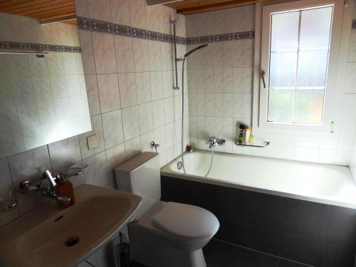 uma casa de banho com um WC, uma banheira e um lavatório. em BASE Cafe em Lauterbrunnen