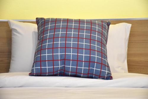 a red and blue plaid pillow on a bed at TUCK Me iN in Chiang Mai