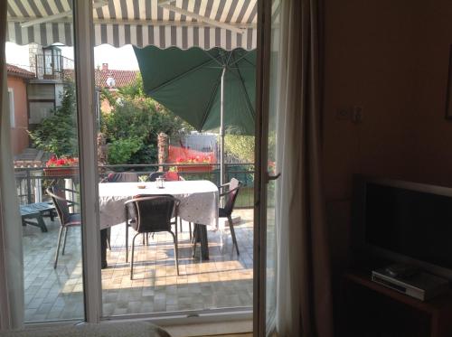 eine Terrasse mit einem Tisch und einem Sonnenschirm auf dem Balkon in der Unterkunft Apartments Boglić in Umag