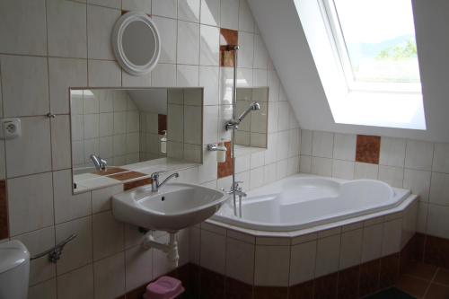 La salle de bains est pourvue d'un lavabo, d'une baignoire et d'une fenêtre. dans l'établissement Penzión BREJK, à Liptovské Sliače