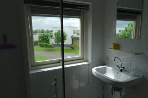 een badkamer met een wastafel en een raam bij vakantiehuisgalamadammen met ligplaats boot in Koudum