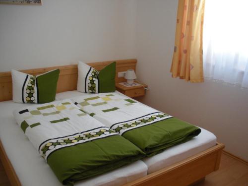 a bed with green and white sheets and pillows at Brunnerhof in Strassen