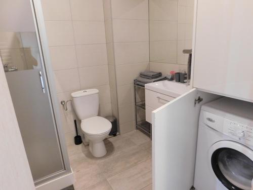 a small bathroom with a toilet and a washing machine at Apartament Pogodny in Łeba