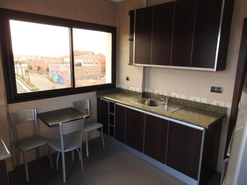 a small kitchen with a table and a window at Résidence Vladimiro Ariano in Laayoune