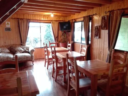 sala de estar con mesas, sillas y sofá en Hostal Monica, en Pucón