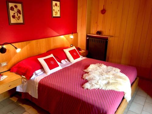 a bedroom with a large bed with red walls at Hotel Carrara in Serina