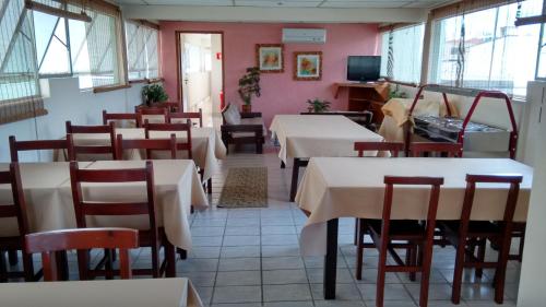 un restaurante con mesas, sillas y paredes rosas en Podium Hotel, en São Caetano do Sul