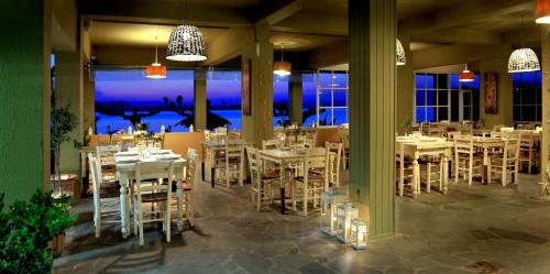 a restaurant with white tables and chairs and a view of the ocean at Venus Beach Hotel in Nea Stira