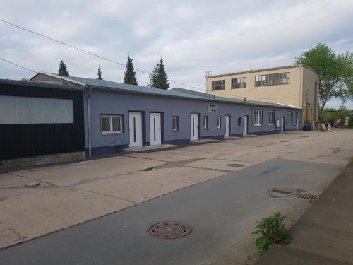 a long blue building with white doors on a street at Pension zum Bauhof in Zwickau