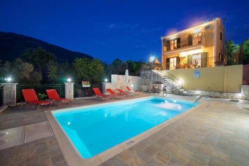 a swimming pool in front of a house at night at stunning tranquil villa with private pool in Sami