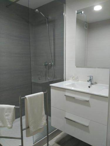 a white bathroom with a shower and a sink at Hotel Puente de los Santos in Tapia de Casariego