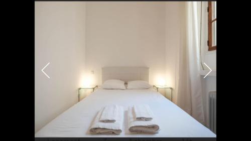 un lit blanc avec deux serviettes dessus dans l'établissement Ice coeur de Cannes, à Cannes