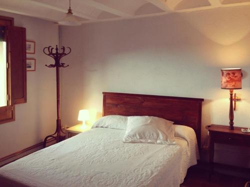 um quarto com uma cama com lençóis brancos e 2 candeeiros em Cal Son em Alpens