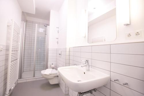 a white bathroom with a sink and a toilet at Hafenapartments Warnemünde in Warnemünde