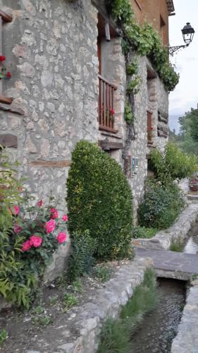 a stone building with flowers and a balcony at Casa Rural Molí de Fòrnols in Fornols
