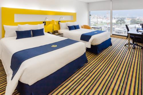 a hotel room with two beds and a desk at Wyndham Bogota in Bogotá