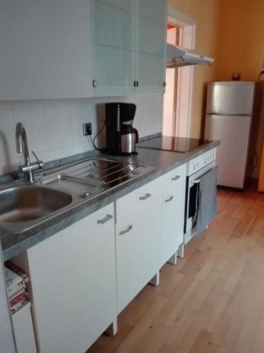 a kitchen with white cabinets and a sink and a refrigerator at Gästezimmer Fuchs in Neuhausen auf den Fildern