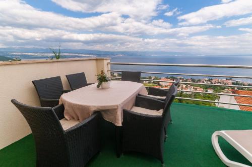 a table on a balcony with a view of the ocean at Apartments Belvedere Lovran in Lovran