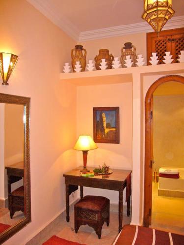a room with a table with a lamp and a mirror at Riad Rabahsadia in Marrakech