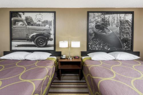 a hotel room with two beds and a car on the wall at Super 8 by Wyndham Bloomington in Bloomington